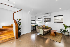 Open-plan living room renovation in Bardon Brisbane with polished concrete floors, timber staircase, and modern study nook
