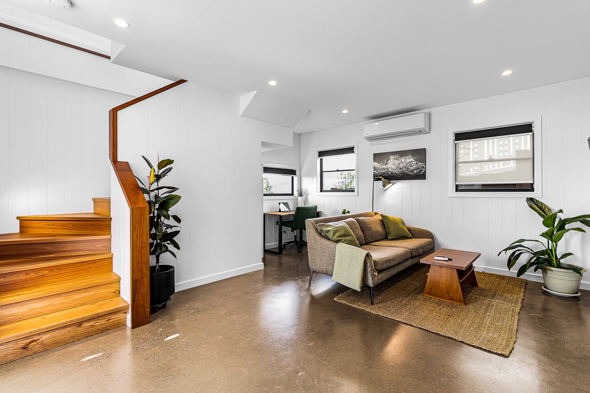 Open-plan living room renovation in Bardon Brisbane with polished concrete floors, timber staircase, and modern study nook