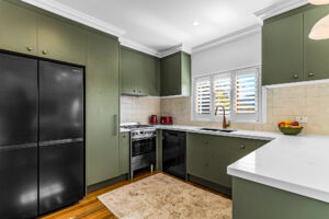 Queenslander renovation Bardon Brisbane – custom kitchen with stone benchtop, green cabinetry, and pendant lighting.